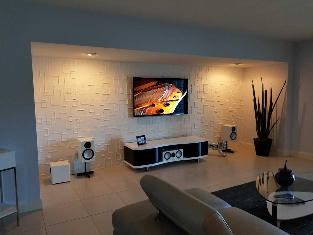 Planned AV installation with wall-mounted TV, tower speakers and subwoofer on textured feature wall